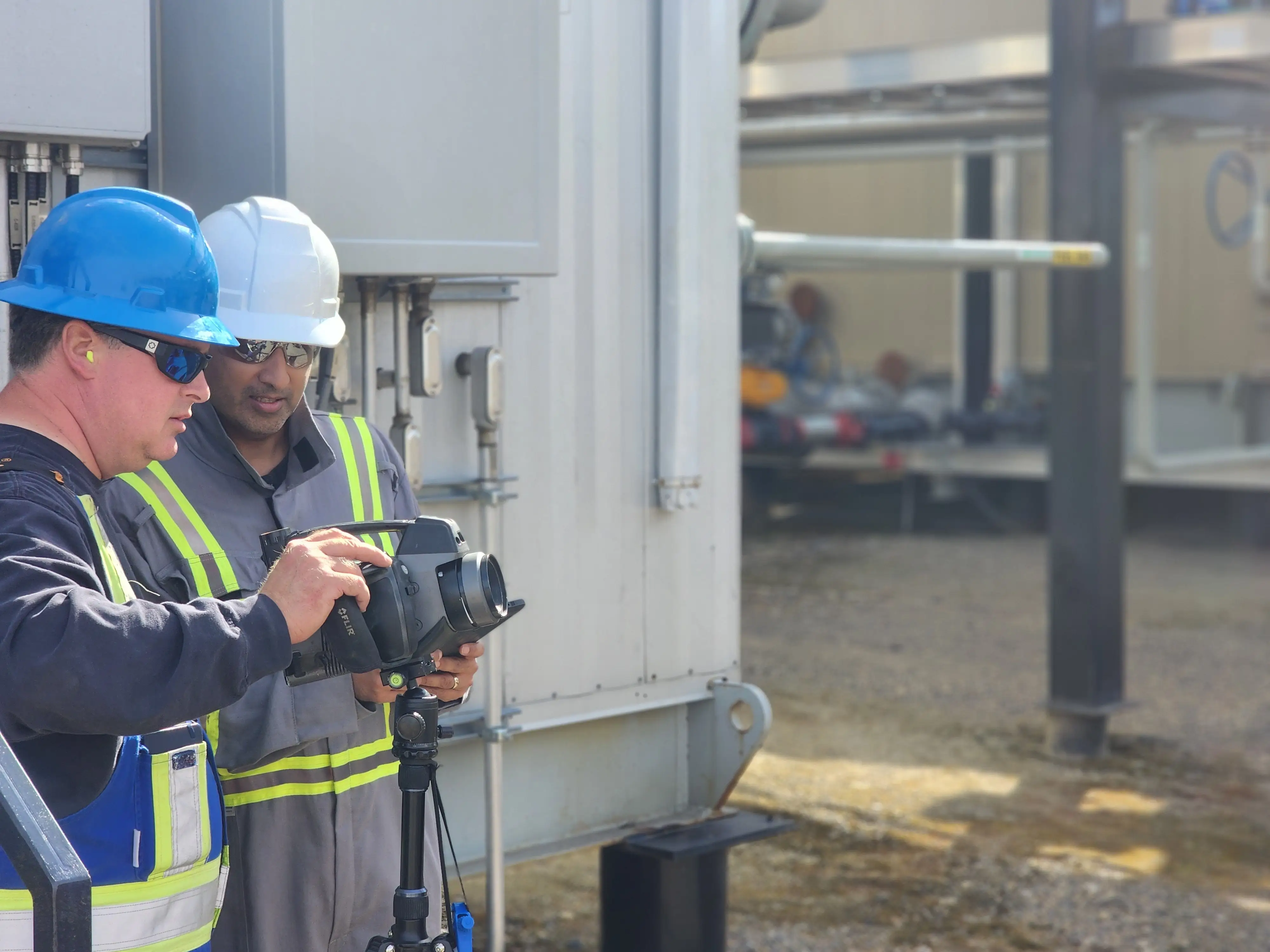 Two field technicians running an optical gas imaging camera survey at a gas facility, inspecting components for leaks.